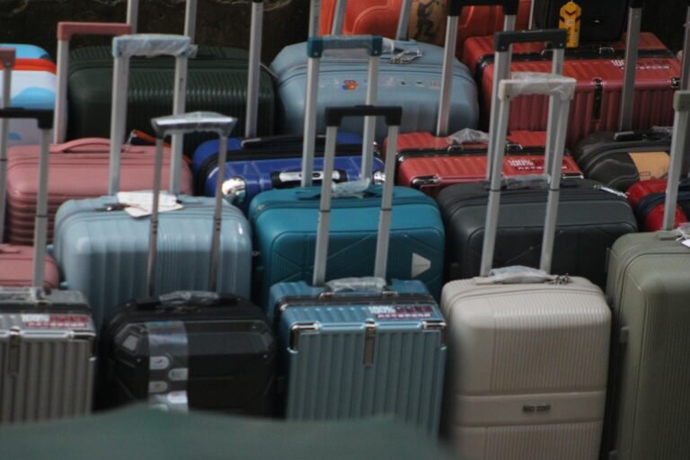 A variety of colorful suitcases with handles extended, ready for travel.