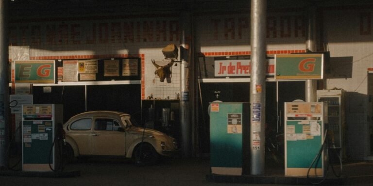 A vintage gas station scene featuring a classic car parked during sunset.