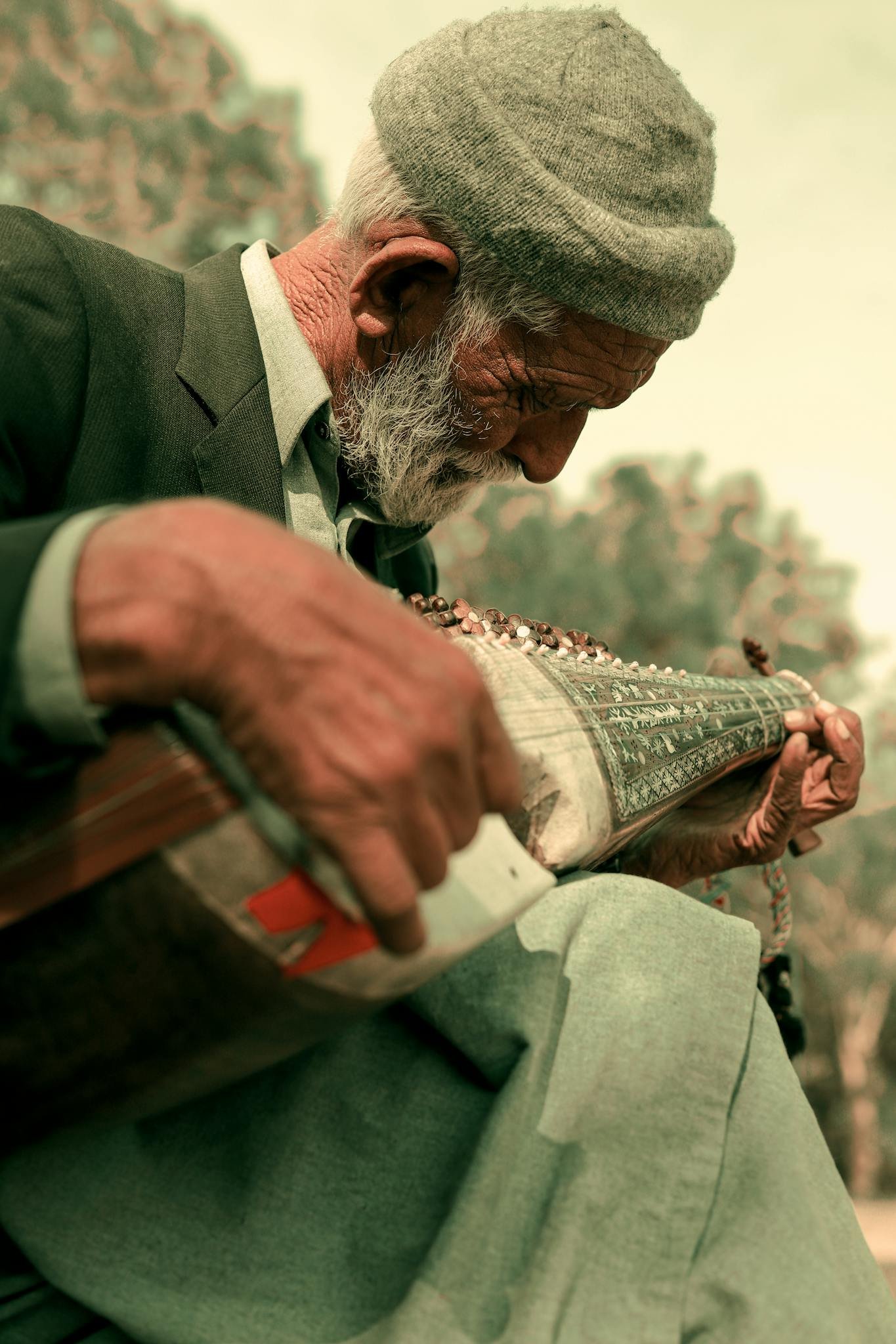 Elderly man outdoors playing a traditional instrument in Islamabad, Pakistan, showcasing cultural heritage.